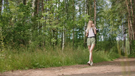 Adult-woman-wearing-shorts-and-t-shirt-hikes-through-woods.-Young-lady-hiking
